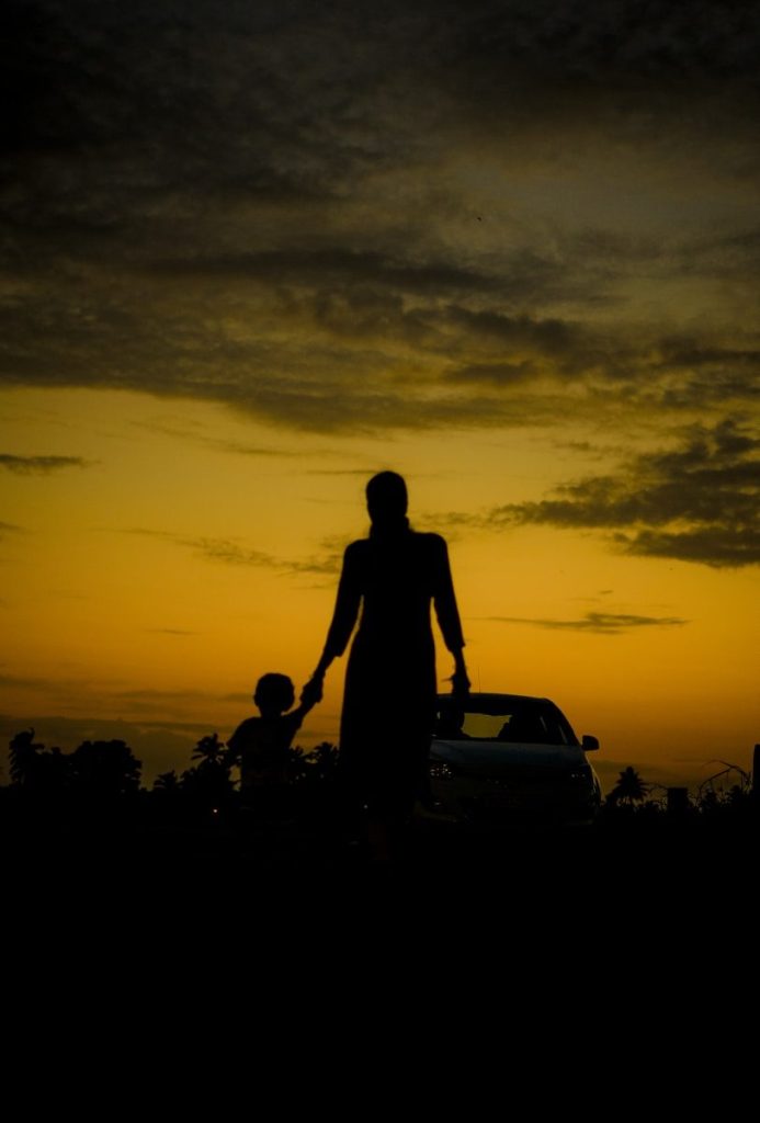 A silhouette of a person holding a child's hand